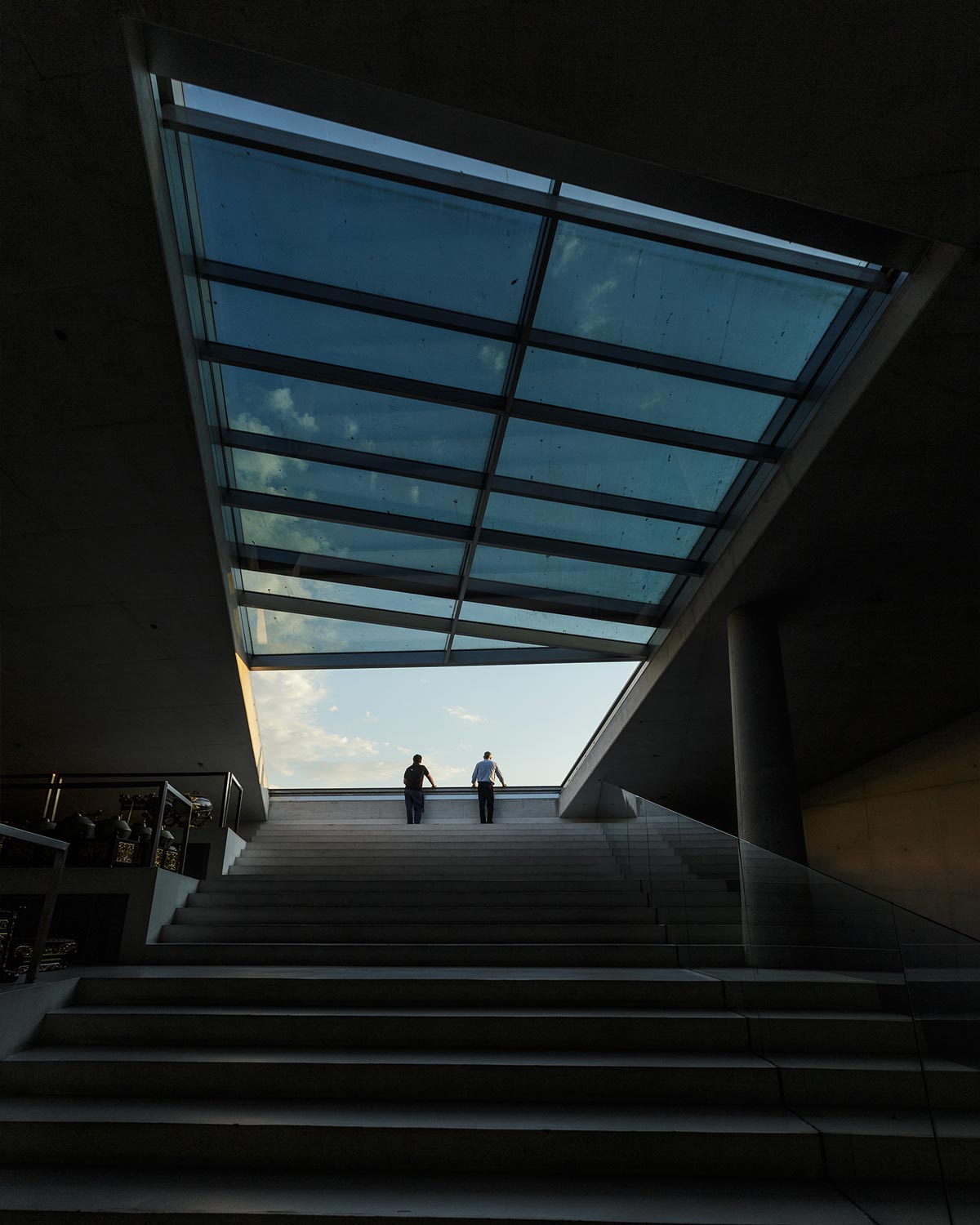 Parte superior da Casa da Música com abertura para o céu, onde duas pessoas em contraluz contemplam a vista num momento de silêncio e luz natural.