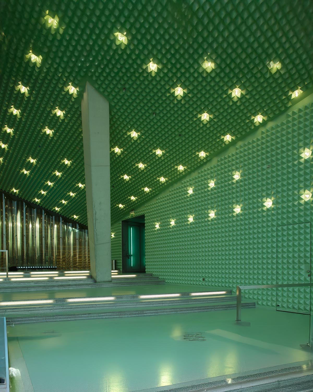 Interior da Casa da Música com isolamento acústico trabalhado, luzes artísticas e tons de turquesa claro. Ambiente claro, com pouca luz natural.