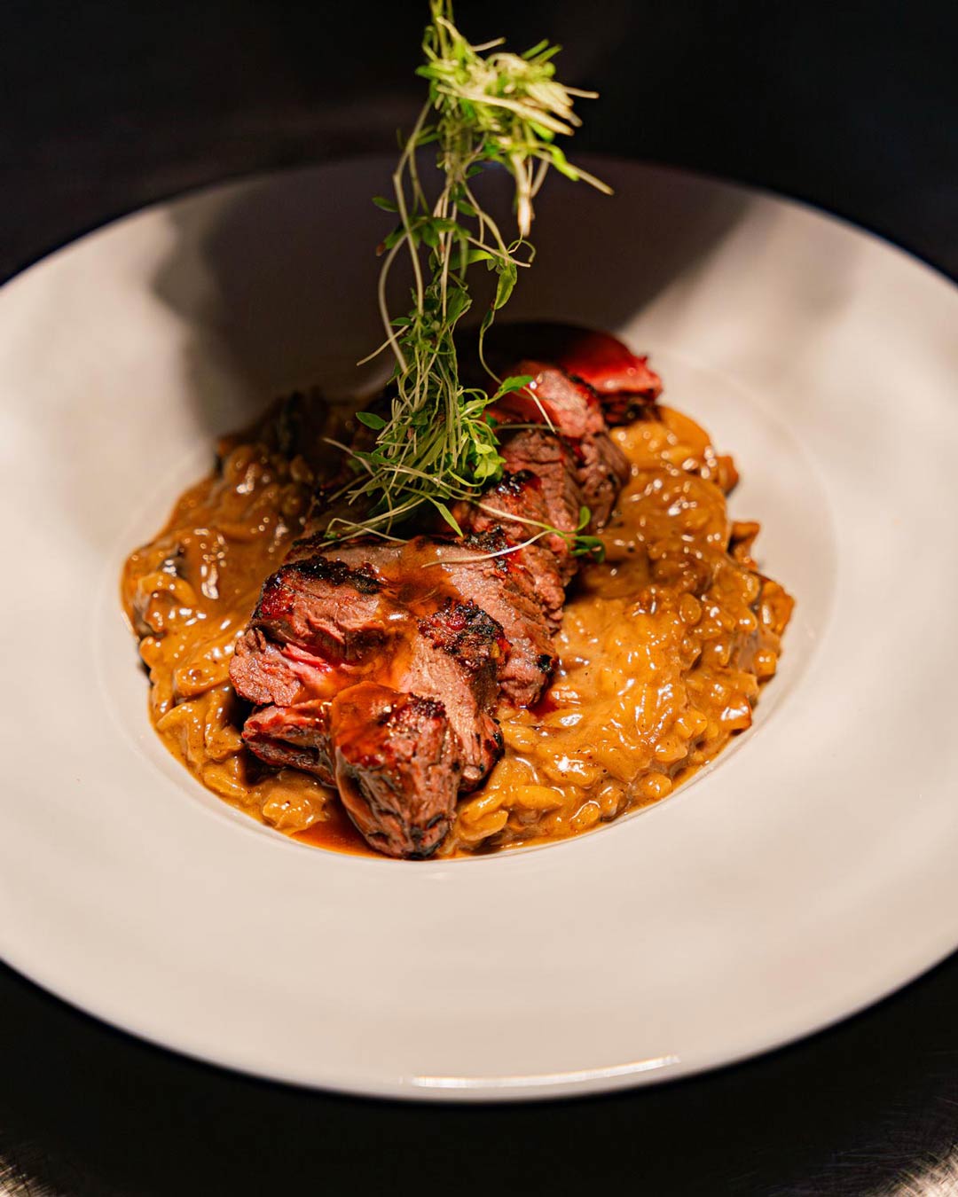 Prato requintado de carne servido no restaurante da Casa da Música, com finalização de ervas frescas e apresentação elegante.